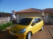 yellow car with 2 girsl jumping at the back