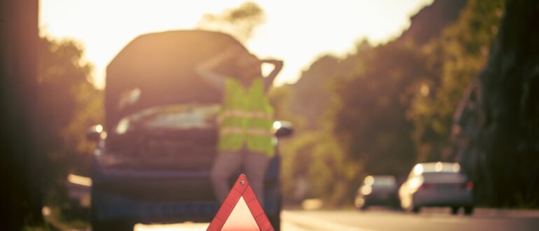 A man is standing next to a broken down car