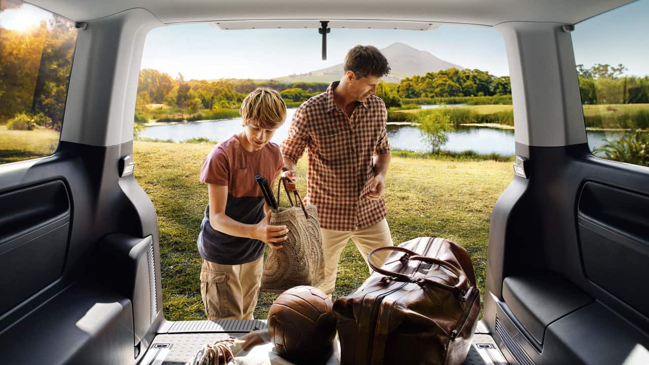 Father and son packing gear in the back of a van