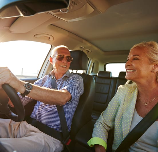 Older couple in a car, male is driving.