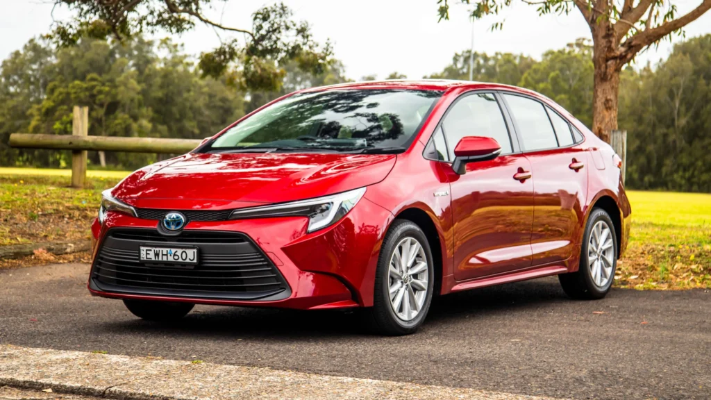red toyota corolla hybrid parked on grey pavement