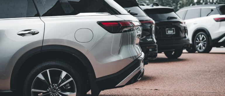 Row of modern SUVs parked at a dealership, viewed from the rear side angle.