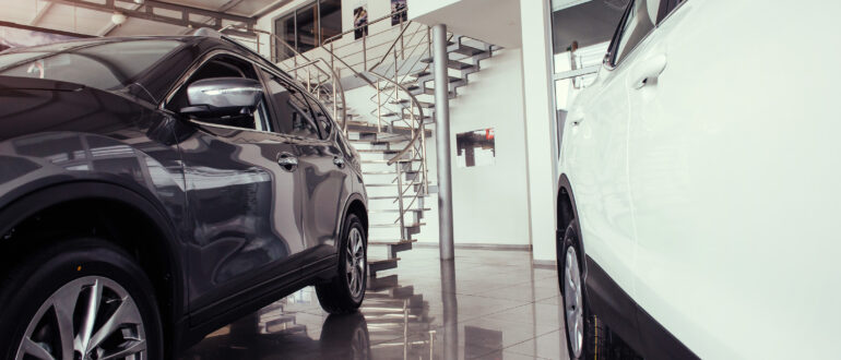 Cars in a spacious showroom with large windows.