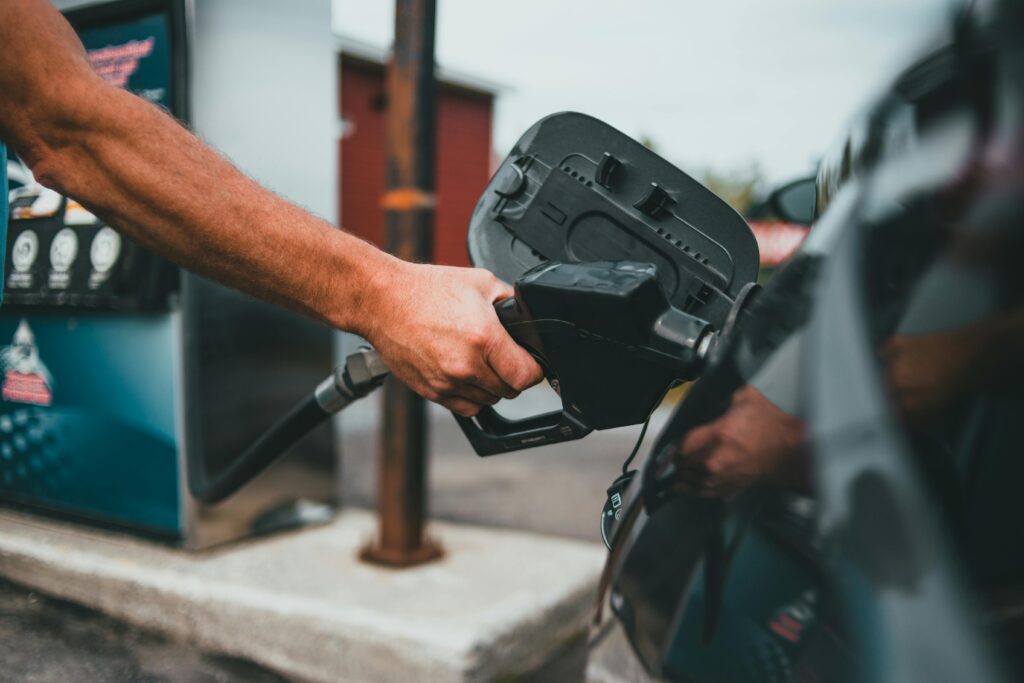 Close-up of a hand holding a nozzle while refuelling a car at a gas station