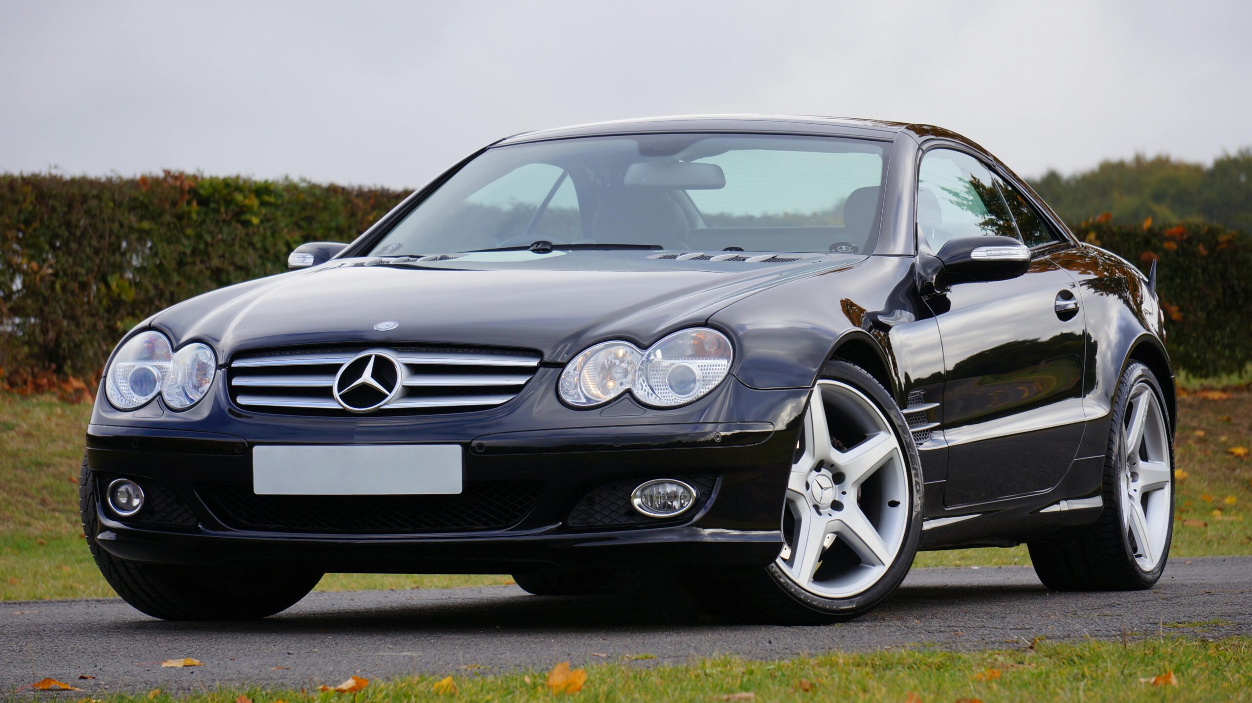 Shiny black Mercedes convertible on an outdoor road in daylight, showcasing luxury and design.